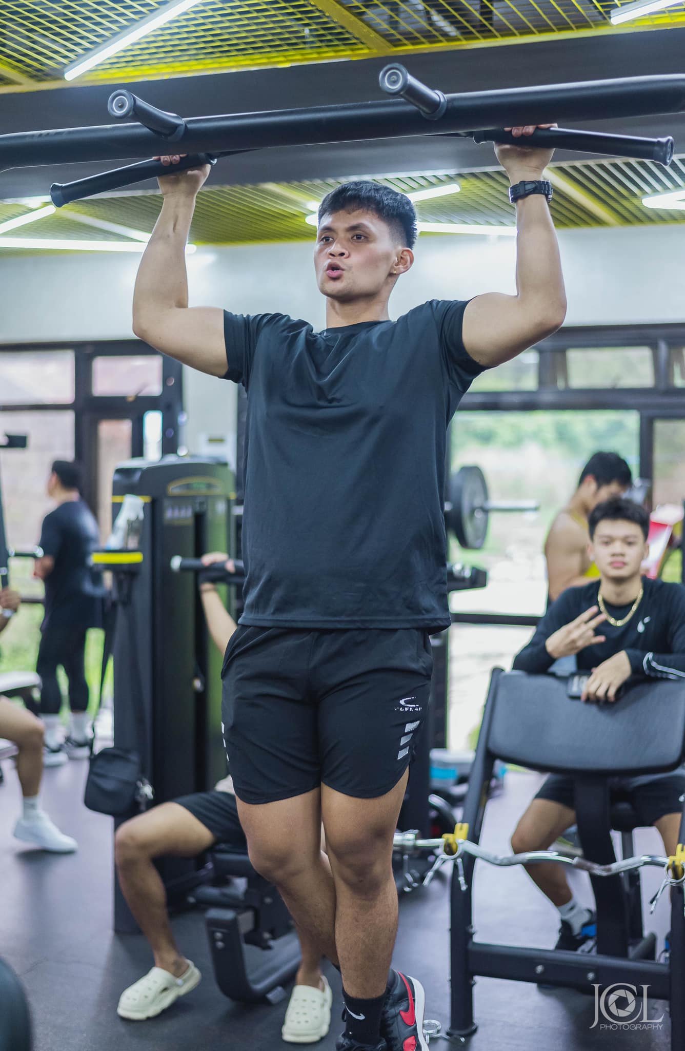 Aaron Noche, coach at Baumann Fit Box, performing a pull-up during a training session in the gym, surrounded by an active and motivating fitness environment.