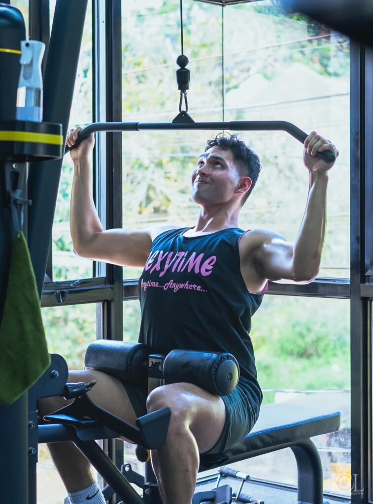 Man performing a pulldown exercise in a gym, demonstrating strength training benefits of regular gym workouts.